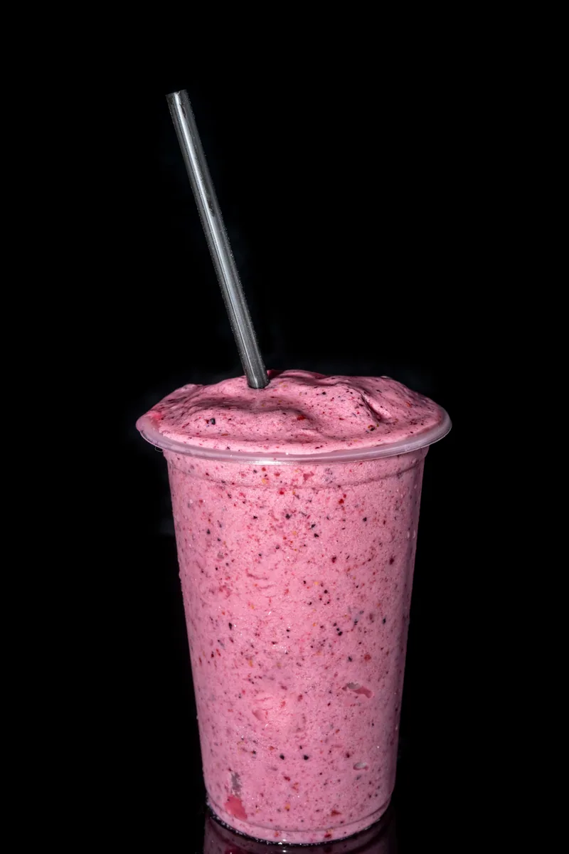 Berry dessert drink photographed against a dark backdrop