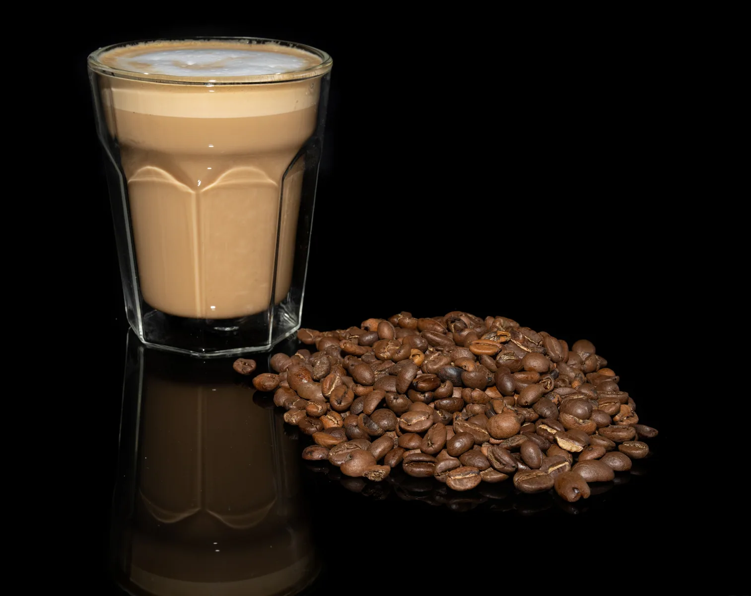 Latte photographed with coffee beans on a dark surface