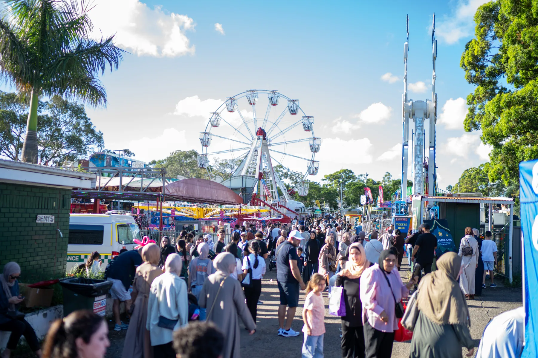 Daytime crowd and rides at a community food event